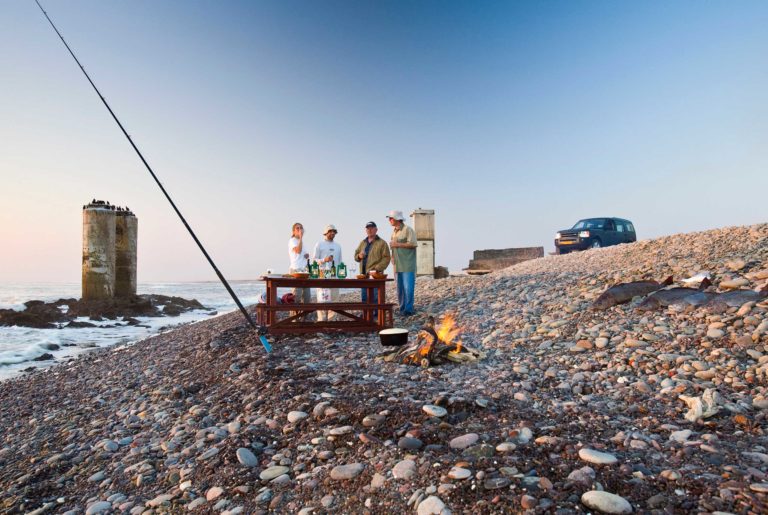 Terrace Bay Namibia – anglers on the rocky beach at sunset