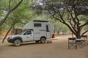 Namibia safari lodge – camper vehicle parked at a shaded site