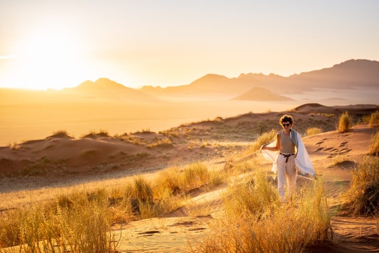 NamibRand accommodation – couple walking through golden grass