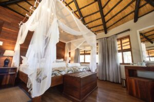Mosquito-netted chalet bedroom at Hakusembe River Lodge