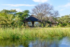 Thatched Hakusembe River Lodge chalets viewed from the Okavango River